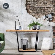 a table with some plants on it in front of a green chair and brick wall