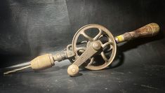 an old metal spool with a wooden handle and two keys attached to it on a black surface