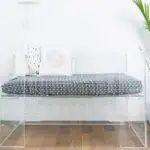 a glass bench sitting on top of a wooden floor next to a potted plant