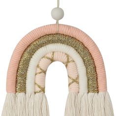 a pink and white hanging decoration with fringes on it's sides, in the shape of a rainbow