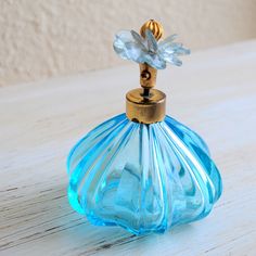 a blue glass perfume bottle sitting on top of a wooden table