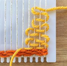 an orange and yellow piece of yarn sitting on top of a white board