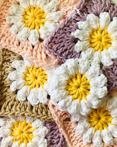 several crocheted flowers are arranged on top of each other, with yellow and white petals