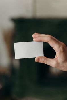 a person's hand holding a white business card in front of a fire place