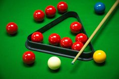 pool balls and cues on a green billiards table with one cue in the middle