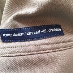 a label on the back of a shirt that says, romanticism handled with dispplinine