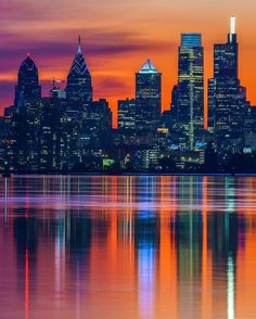 the city is lit up at night and reflecting in the water with its lights on