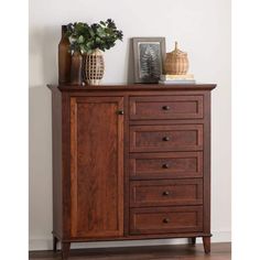 a wooden cabinet with drawers and vases on top