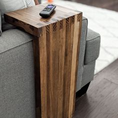 a remote control sitting on top of a wooden table next to a gray couch in a living room