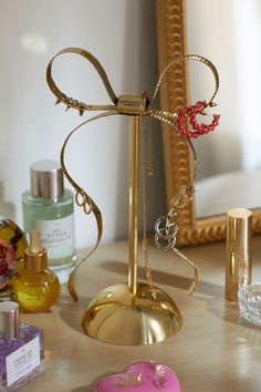 an assortment of jewelry on a table in front of a mirror with a gold frame