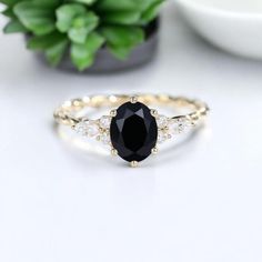 a black and white diamond ring sitting on top of a table next to a potted plant