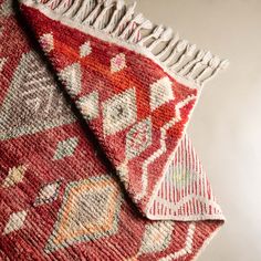 a red and white rug with fringes on the bottom is laying on a table