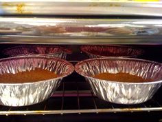 two pie pans sitting in an oven with tin foil