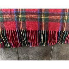 a red and green plaid blanket sitting on top of a gray couch next to a pair of scissors