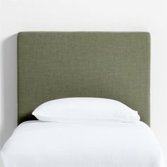 a green headboard with white sheets and pillows