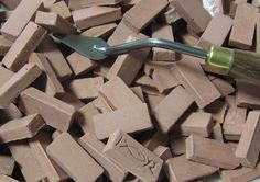 a large pile of brown bricks with a green handled toothbrush