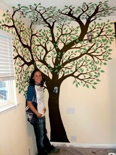 a woman standing next to a tree painted on the wall