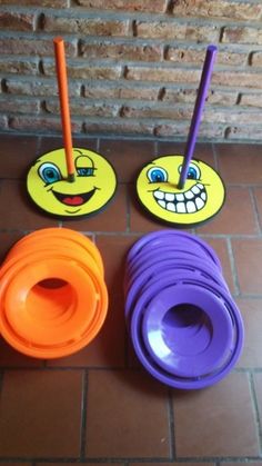 three different colored cups with faces on them sitting on a tile floor next to a brick wall