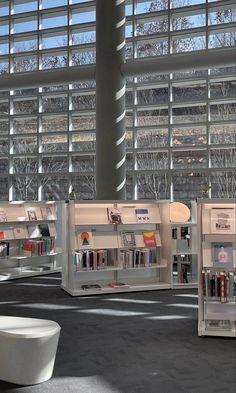 the interior of a library with several bookshelves in front of large glass windows