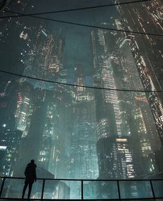 a man standing on top of a tall building in the middle of a city at night