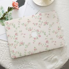 an open laptop computer sitting on top of a table next to a flowery bouquet