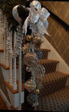 christmas decorations are hanging on the banisters in this staircase decorated with silver and white ornaments