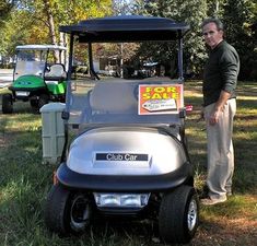 a man standing next to a golf cart with a for sale sign on the back