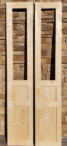 two wooden doors sitting next to each other in front of a stone wall and wood floor