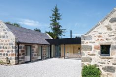 two stone buildings with windows on each side and one building has an open door in the middle