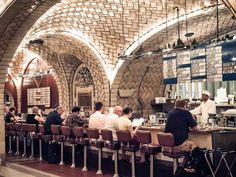 people are sitting at the bar in an old building with arched ceilings and stone arches