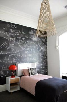 a bedroom with a chalkboard wall behind the bed