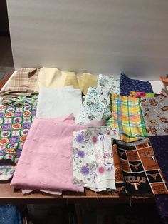 many different colored shirts are on a wooden table and one is folded up to show the pattern