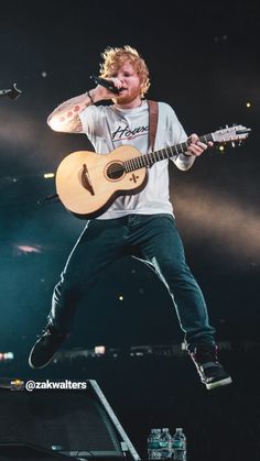 a man with an acoustic guitar on stage