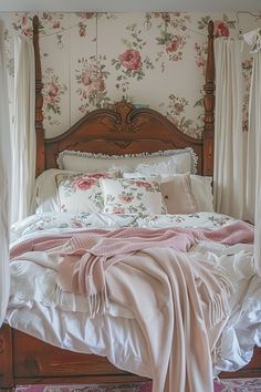 a bed with white sheets and pink flowers on the wall next to it's headboard