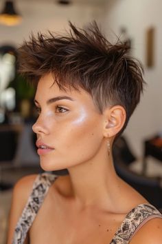 Person with short, spiky hair and a hoop earring, looking to the side in a well-lit room.