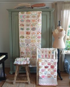 a chair and foot stool in front of a green cabinet with a quilt on it