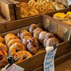 many different types of croissants on display in wooden boxes with price tags