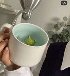 a person holding a cup with a small green bird in it