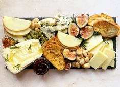 an assortment of cheeses and nuts on a slate platter