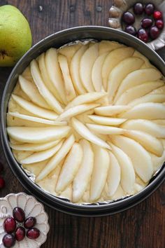 an apple and cranberry tart is shown in a pie pan on a wooden table