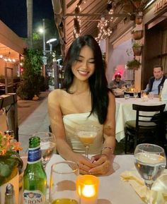 a woman sitting at a table with drinks in front of her and smiling for the camera