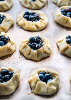 small pastries with blueberries are sitting on a baking sheet and ready to go into the oven