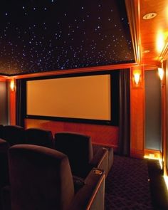 an empty theater room with two seats facing the screen and lights shining on the ceiling