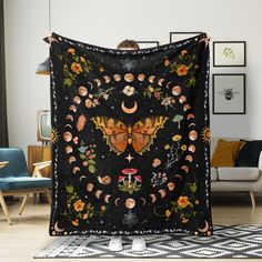 a woman holding up a black blanket with moths and flowers on it