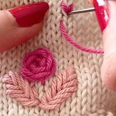 someone is working with yarn to make a heart - shaped decoration on a knitted blanket