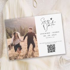 a wedding save the date card with an image of two people holding hands and running through a field