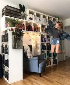 a woman jumping up into the air in front of a bookshelf