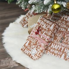 christmas presents wrapped in brown and white wrapping paper under a tree with ornaments on it