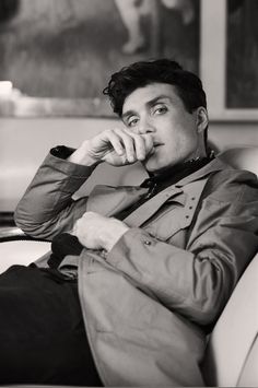 black and white photograph of a man sitting in a chair with his hand on his chin