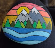 a painted rock with mountains and water on it